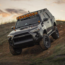 Load image into Gallery viewer, The Old Man Emu 3 inch Lift Kit for 4Runner (10-23) equipped with an Old Man Emu suspension system is confidently driving down a dirt road, conquering uneven terrain with its Nitrocharger shocks and enjoying enhanced off-road performance.