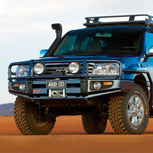 Load image into Gallery viewer, A blue Old Man Emu Toyota Land Cruiser with an impressive ground clearance is parked in the desert.