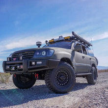 Load image into Gallery viewer, An Old Man Emu 2 inch Lift Kit for LandCruiser 100 Series, Lexus LX470 (98-07) with an enhanced suspension system and increased ground clearance is parked on a dirt road.
