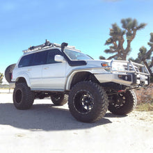 Load image into Gallery viewer, A white Toyota Land Cruiser with the Old Man Emu 4 inch Lift Kit for LandCruiser 80 &amp; 105 Series (90-07) is parked on a dirt road.