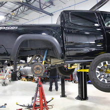 Load image into Gallery viewer, A Toyota Tacoma enhanced with an Old Man Emu suspension system for adjustable damping and outfitted with the OME BP-51 2-3 inch Lift Kit for Tacoma (05-23), giving it a lifted stance on a lift.
