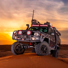 Load image into Gallery viewer, An Old Man Emu Land Cruiser equipped with OME BP-51 Front Coil Over LH BP5190002L for Toyota 4Runner and FJ Cruiser, remote reservoir shock absorbers, and high-temperature hose, driving through the desert at sunset.