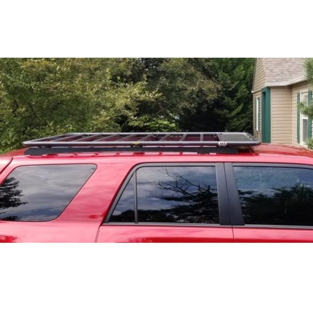 A red SUV with solar panels on the roof and an ARB Flat Roof Rack for Toyota 3813030 for Toyota 4Runner 4th and 5th generation for secure storage.