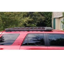 Load image into Gallery viewer, A red SUV with solar panels on the roof and an ARB Flat Roof Rack for Toyota 3813030 for Toyota 4Runner 4th and 5th generation for secure storage.