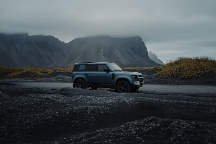 2020 Land Rover Defender 110 off-road vehicle navigating rugged volcanic terrain under overcast sky
