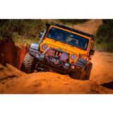 An Old Man Emu orange jeep with excellent shock absorber performance, specifically the ARB Old Man Emu Front Nitrocharger Sport L Series 60066M, is driving down a dirt road.