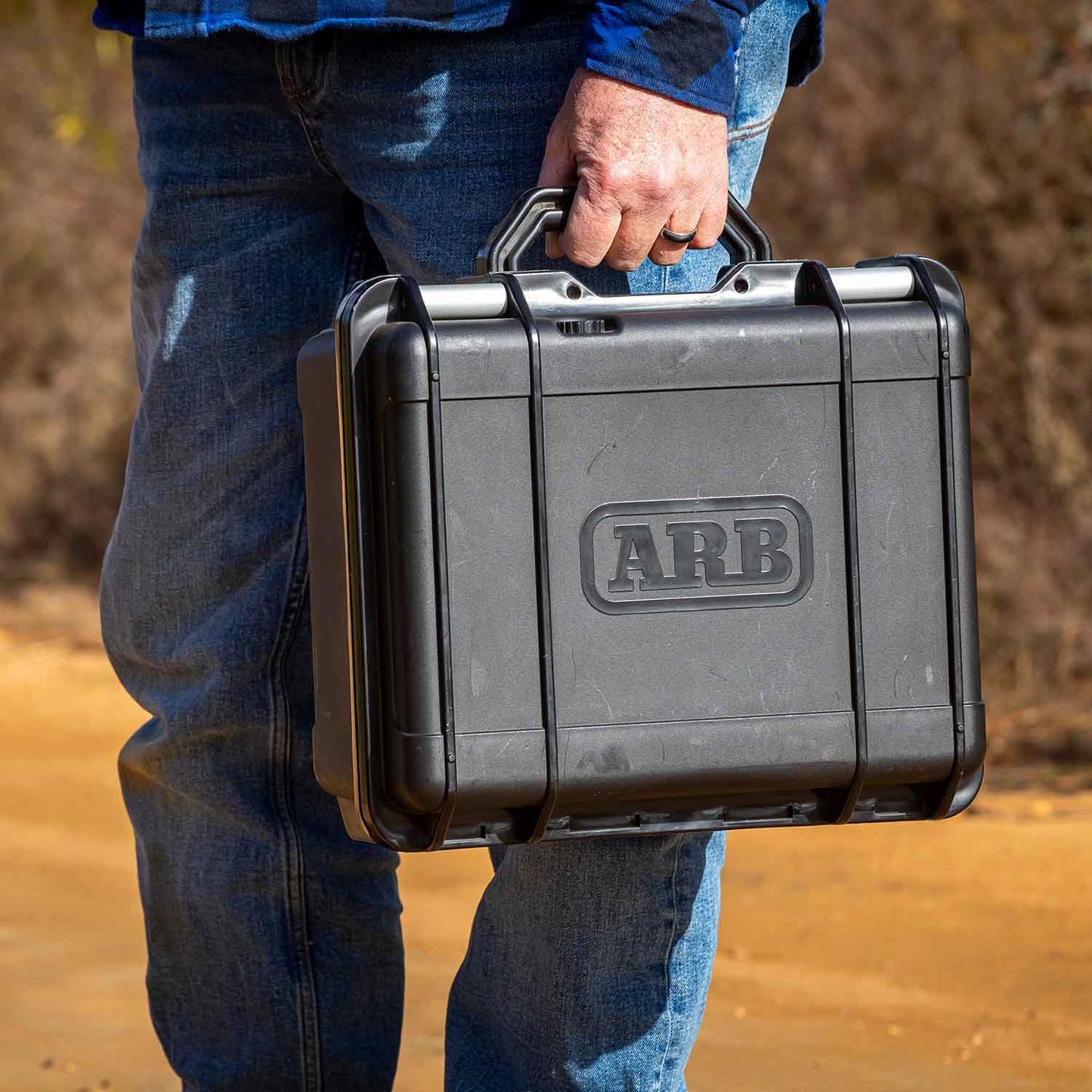 ARB Portable 12V Air Compressor Single Motor CKMP12V2 in rugged black carrying case held by person outdoors near 2007-2018 Jeep Wrangler JK context