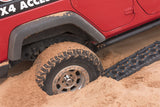 ARB TRED Pro Blue Recovery Boards TREDPROBU positioned next to stuck tire of red 4-door Jeep Wrangler in sandy terrain