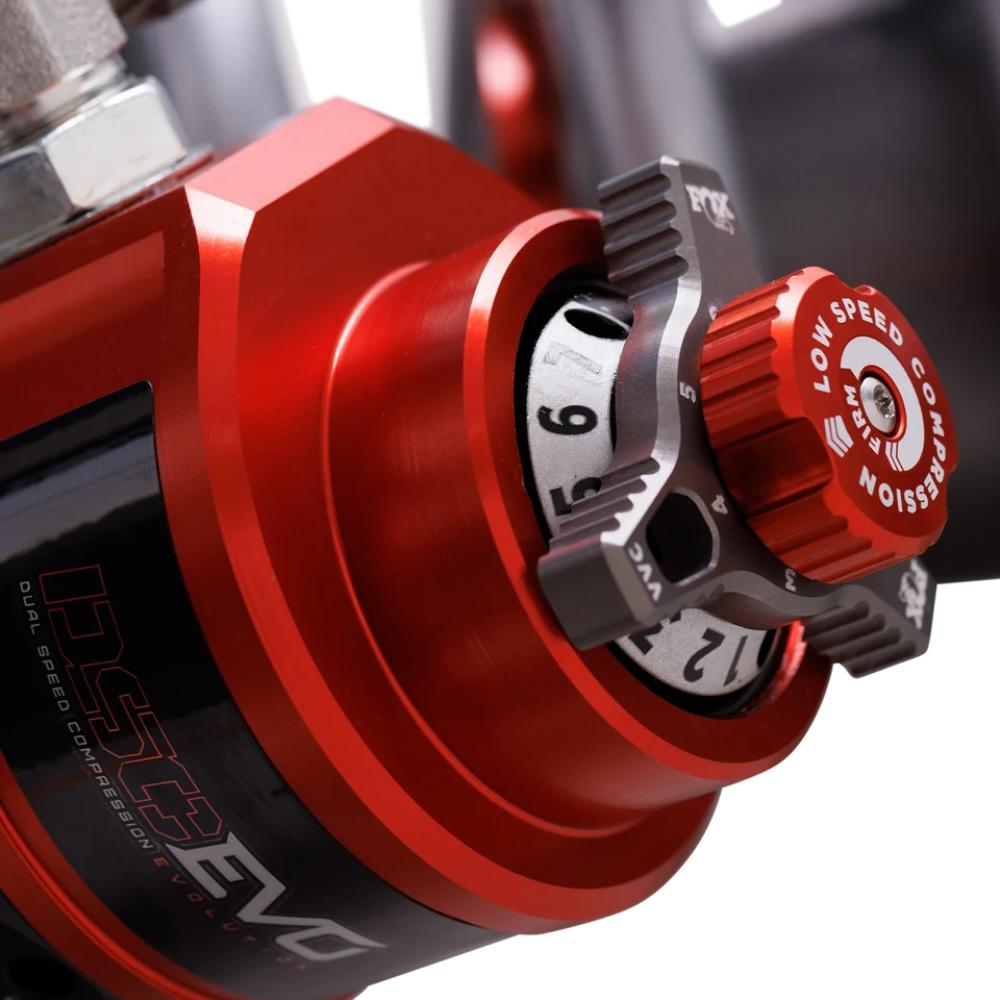 Close-up of a red off-road shock absorber with dual-speed compression adjustment dial