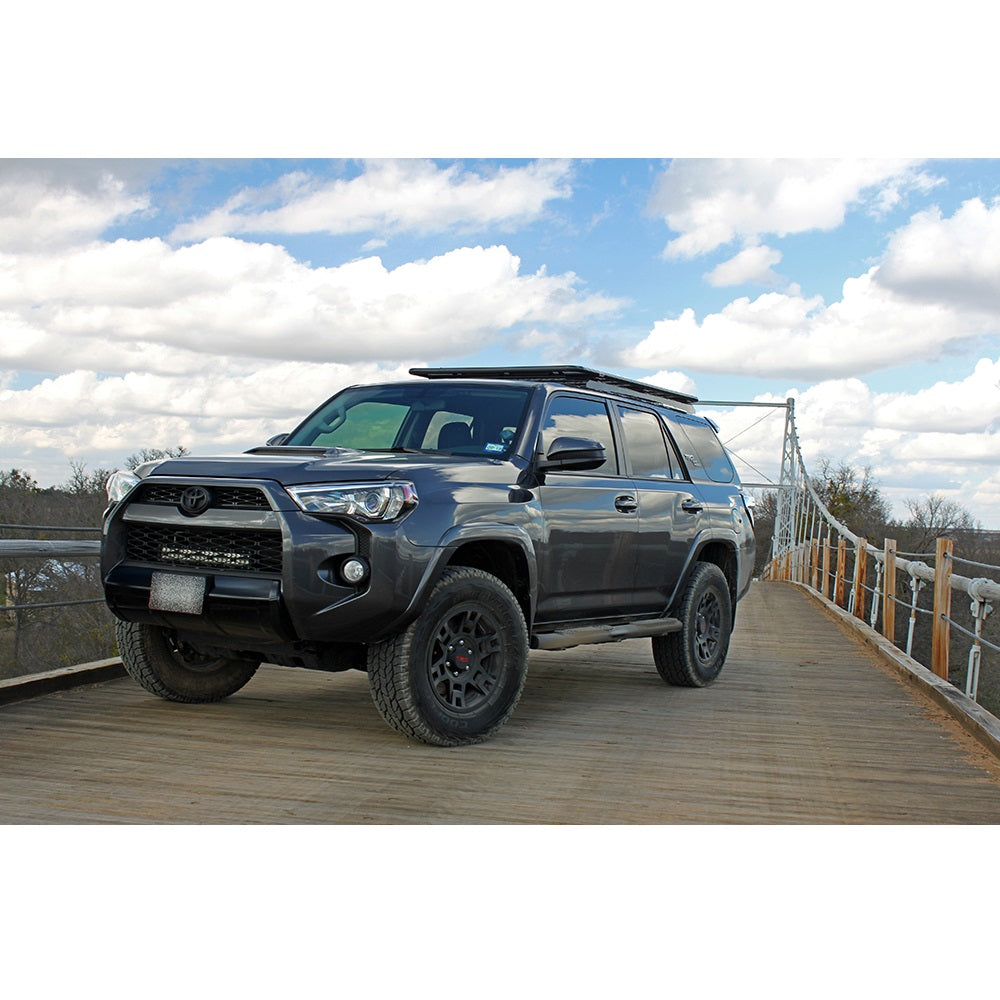 The Toyota 4Runner, equipped with the Bilstein B8 5100 2 inch 4Runner (10-ON) Lift Kit w/ OME Springs - Front Shock Assembly from Bilstein, is parked on a bridge.