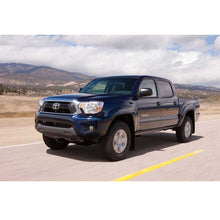 Load image into Gallery viewer, The blue Toyota Tacoma, equipped with the Bilstein B8 6112/5160 0-2 inch Tacoma (05-15) Lift Kit w/ OME Leaf Springs - Front Shocks Assembly, is embarking on off-road adventures down the road.