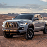 An off-road truck with the Bilstein B8 6112/5160 0-2 inch Tacoma (16-23) Lift Kit w/ OME Leaf Springs suspension climbing up a hill.