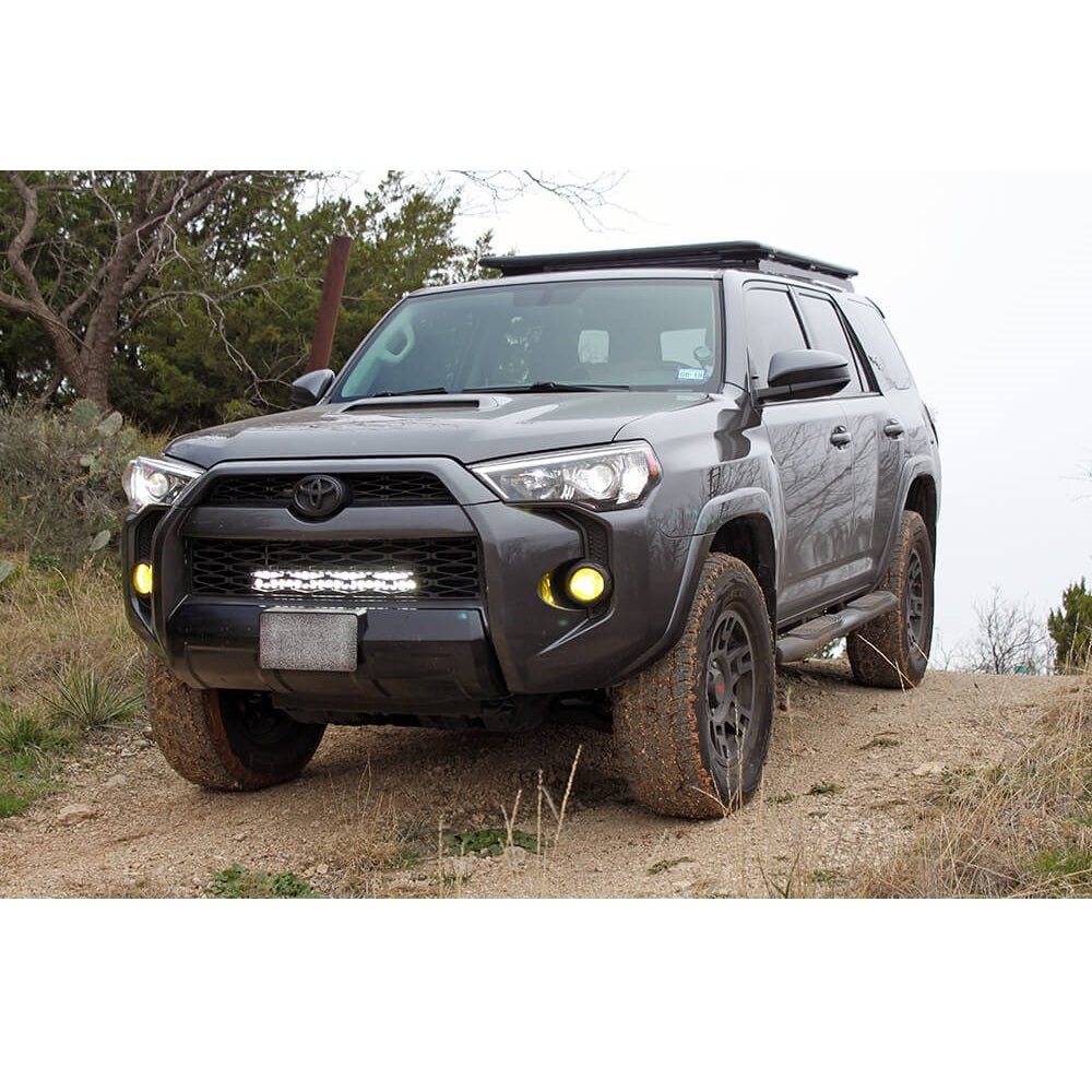 The Toyota 4Runner, equipped with the Bilstein B8 8112 2.5 inch 4Runner (10-ON) Lift Kit w/ OME Springs suspension system from Bilstein, is parked on a dirt road showcasing its exceptional off-road performance.