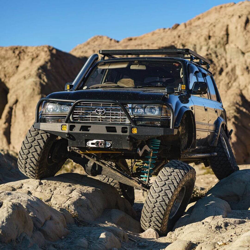 Lifted Toyota 4Runner with off-road suspension, winch bumper, roof rack, and oversized tires navigating rocky terrain