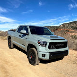The 2019 Toyota Tundra, equipped with the KING 2 - 3 inch Lift Kit for Tundra (07-21) by King Shocks for enhanced off-road performance, is parked on a dirt road, showcasing its stability.