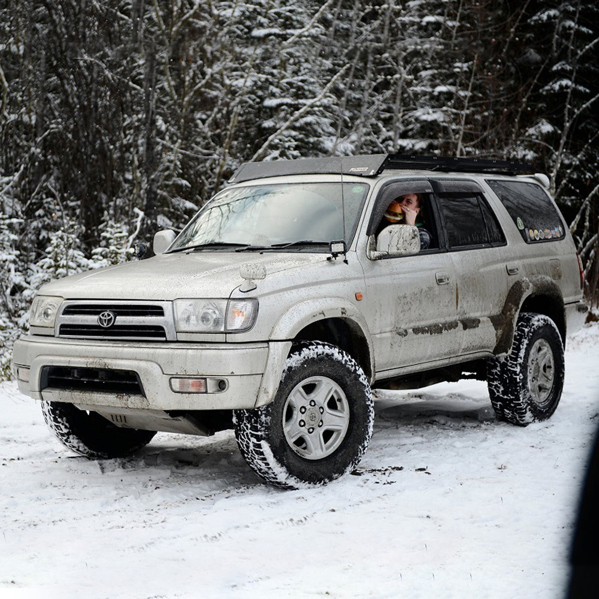 A silver Toyota 4Runner, equipped with an OME 2 inch Lift Kit for 4Runner (96-02) by Old Man Emu, confidently navigates through the snowy terrain with its increased ground clearance.
