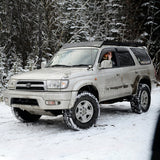 A silver Toyota 4Runner, equipped with an OME 2 inch Lift Kit for 4Runner (96-02) by Old Man Emu, confidently navigates through the snowy terrain with its increased ground clearance.