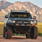 A Toyota Tacoma parked on a dirt road with mountains in the background, boasting impressive ground clearance thanks to its Nitrocharger shocks and OME 2 inch Lift Kit for 4Runner (03-09).