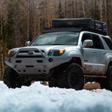 A silver Toyota 4Runner with an Old Man Emu OME 2 inch Lift Kit for 4Runner (03-09) suspension system is parked in the snow, showcasing its impressive ground clearance.