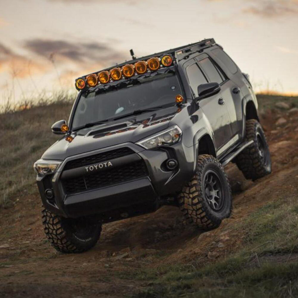 The Old Man Emu 2 inch Lift Kit for 4Runner (10-23) is driving down a dirt road, showcasing its impressive suspension system and ground clearance abilities.