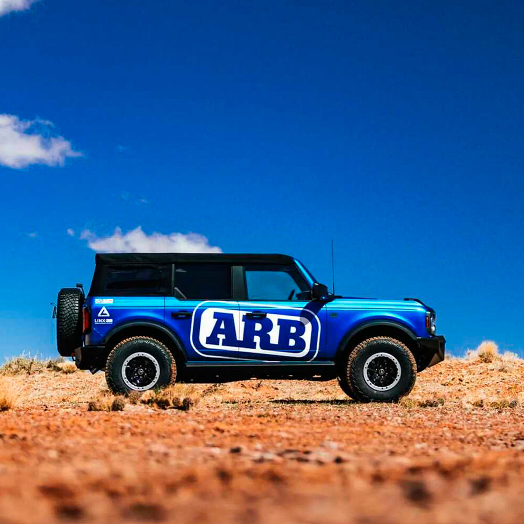 A blue Old Man Emu Ford Explorer with an enhanced ride quality is parked in the desert.