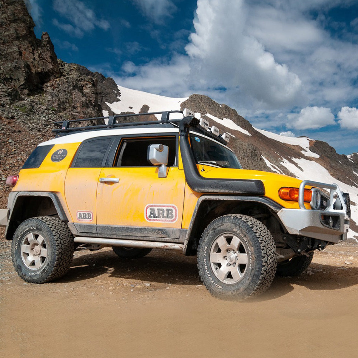 A yellow Toyota FJ Cruiser with an impressive suspension system parked on a dirt road, boasting exceptional ground clearance thanks to the Old Man Emu OME 2 inch Lift Kit for FJ Cruiser (03-09) - Front Shocks Assembly upgrades.