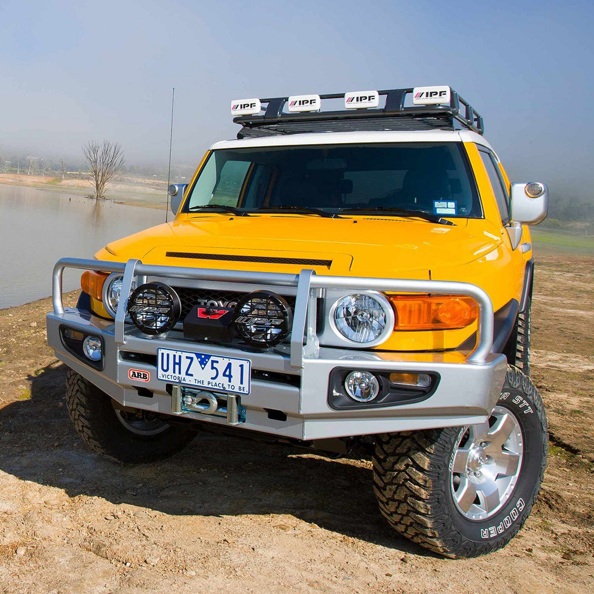 A yellow Old Man Emu Toyota FJ Cruiser with an OME 2 inch Lift Kit for FJ Cruiser (03-09) - Front Shocks Assembly for increased ground clearance.