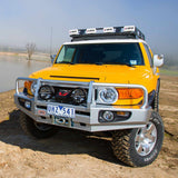 A yellow Old Man Emu Toyota FJ Cruiser with an OME 2 inch Lift Kit for FJ Cruiser (03-09) - Front Shocks Assembly for increased ground clearance.