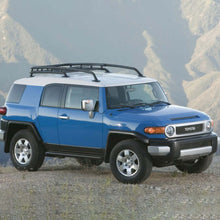 Load image into Gallery viewer, A blue Toyota FJ Cruiser with an OME 2.5 inch Lift Kit for FJ Cruiser (03-09) by Old Man Emu is parked on a hillside, showcasing its impressive ground clearance.