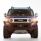 The front end of a blue Toyota FJ Cruiser with an impressive ground clearance, fitted with the OME 2 inch Lift Kit for FJ Cruiser (10-ON) - Front Shocks Assembly by Old Man Emu.