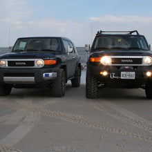 Load image into Gallery viewer, Two Old Man Emu 2 inch Lift Kit for FJ Cruiser (10-ON) equipped Toyota FJ Cruisers parked on the beach with an enhanced suspension system featuring Old Man Emu Nitrocharger shocks.