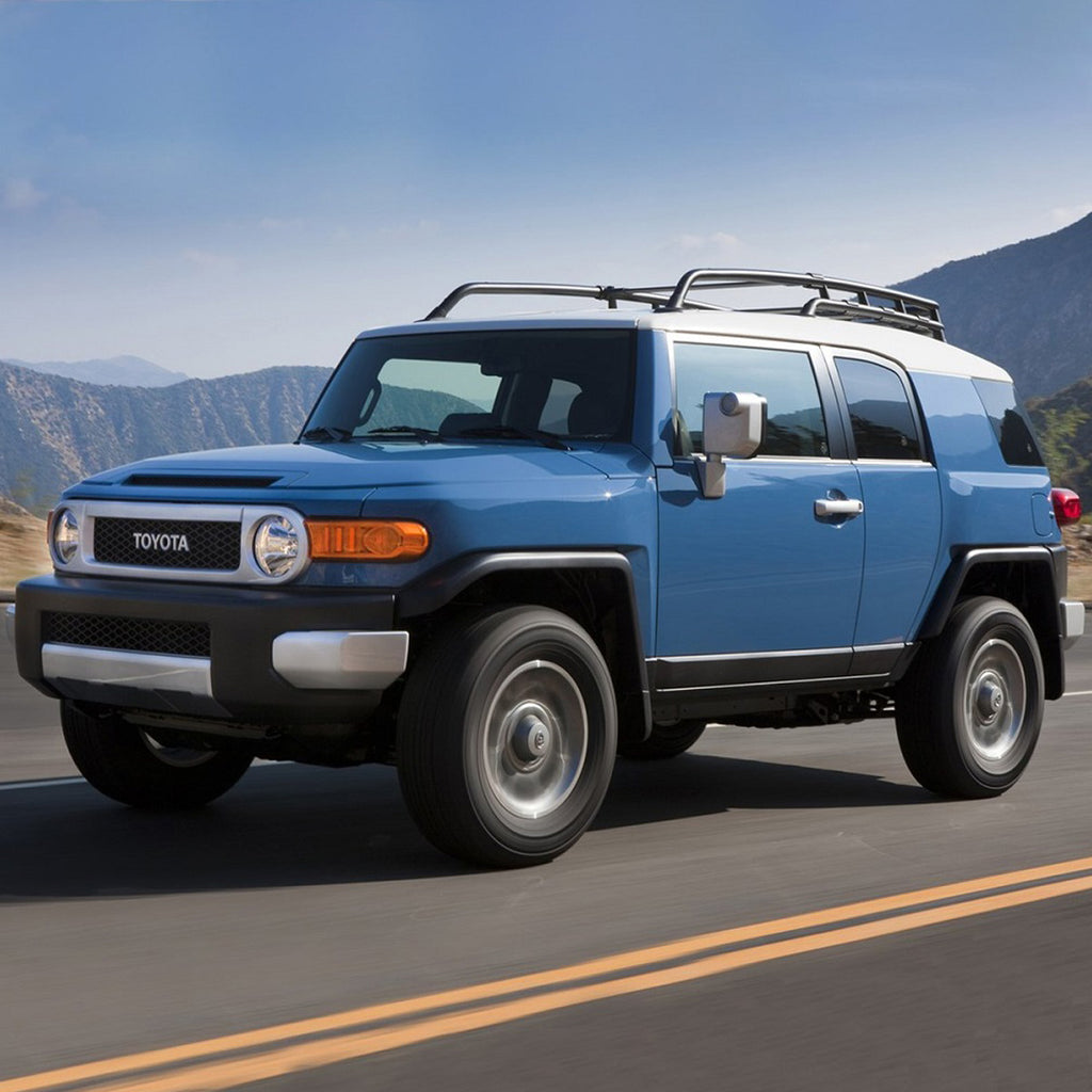 The blue Old Man Emu Toyota FJ Cruiser is driving down the road with impressive ground clearance.