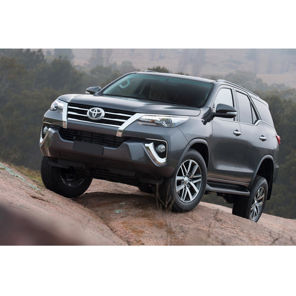 The 2018 Old Man Emu Toyota Fortuner with great ground clearance is driving on a rock.