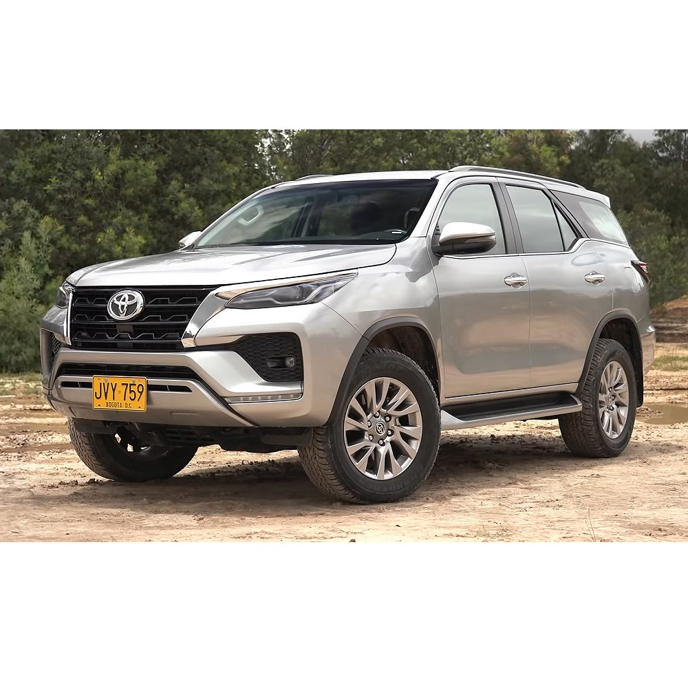 A silver Old Man Emu Toyota Fortuner with impressive ground clearance parked on a dirt road.