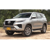 A silver Old Man Emu Toyota Fortuner with impressive ground clearance parked on a dirt road.