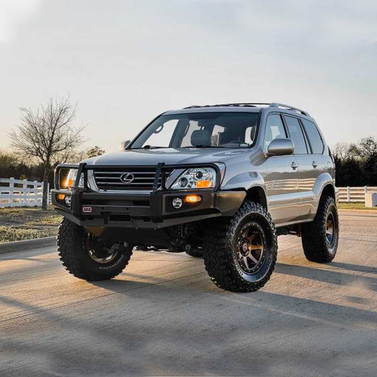 A gray Old Man Emu SUV with outstanding ground clearance is parked on a gravel road, thanks to its reliable OME 2.5 inch Lift Kit for Lexus GX470 (03-09) - Front Shocks Assembly suspension system.