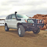 A white Old Man Emu Toyota Land Cruiser with an OME 3 inch Lift Kit for Lexus GX470 (03-09) - Front Shocks Assembly parked on a dirt road, offering excellent ground clearance.