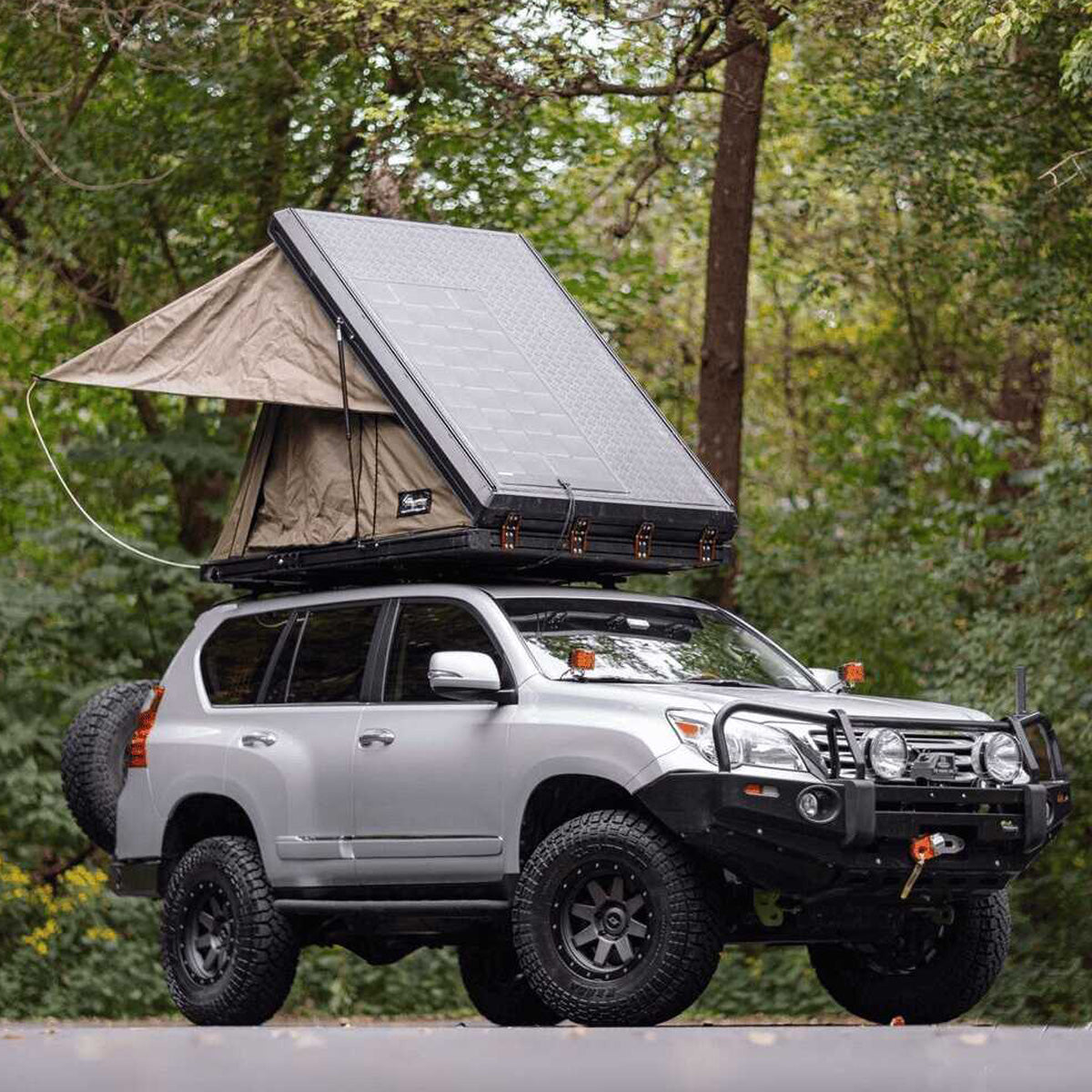 An enhanced Toyota Land Cruiser with an Old Man Emu 2 inch Lift Kit for Lexus GX460 (10-23) - Front Shocks Assembly suspension system for increased ground clearance and a tent on top.