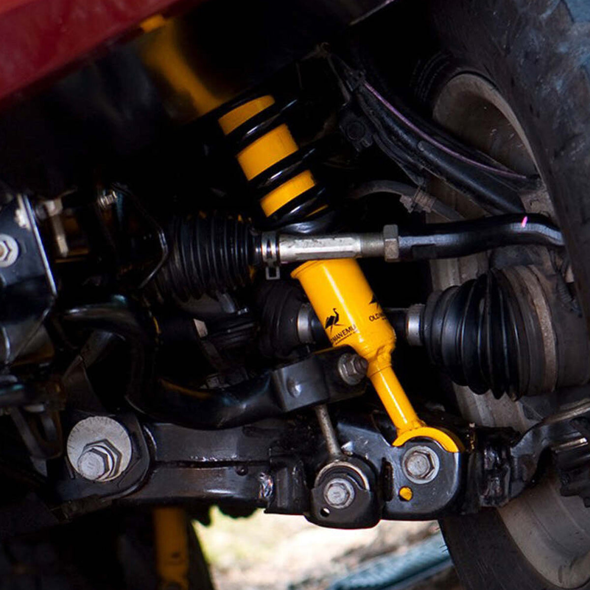 A close up of a vehicle's suspension system featuring the Old Man Emu OME 2.5 - 3 inch Essentials Lift Kit for Hilux Revo, Rocco, SR5 (15-22) and Nitrocharger shocks.