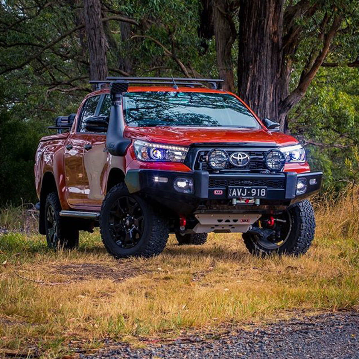 A Toyota Hilux, equipped with an Old Man Emu OME 2.5 - 3 inch Essentials Lift Kit for Hilux Revo, Rocco, SR5 (15-22) suspension system and Nitrocharger shocks, parked on a dirt road.