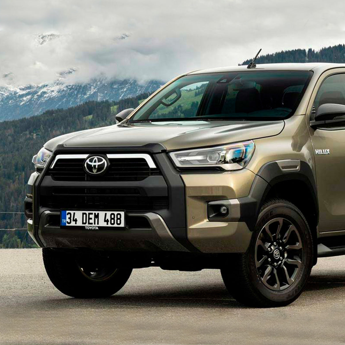 The 2019 Toyota Tacoma, equipped with the OME 2.5 - 3 inch Essentials Lift Kit for Hilux Revo, Rocco, SR5 (15-22) from Old Man Emu, is parked in front of mountains, showcasing its increased ground clearance.