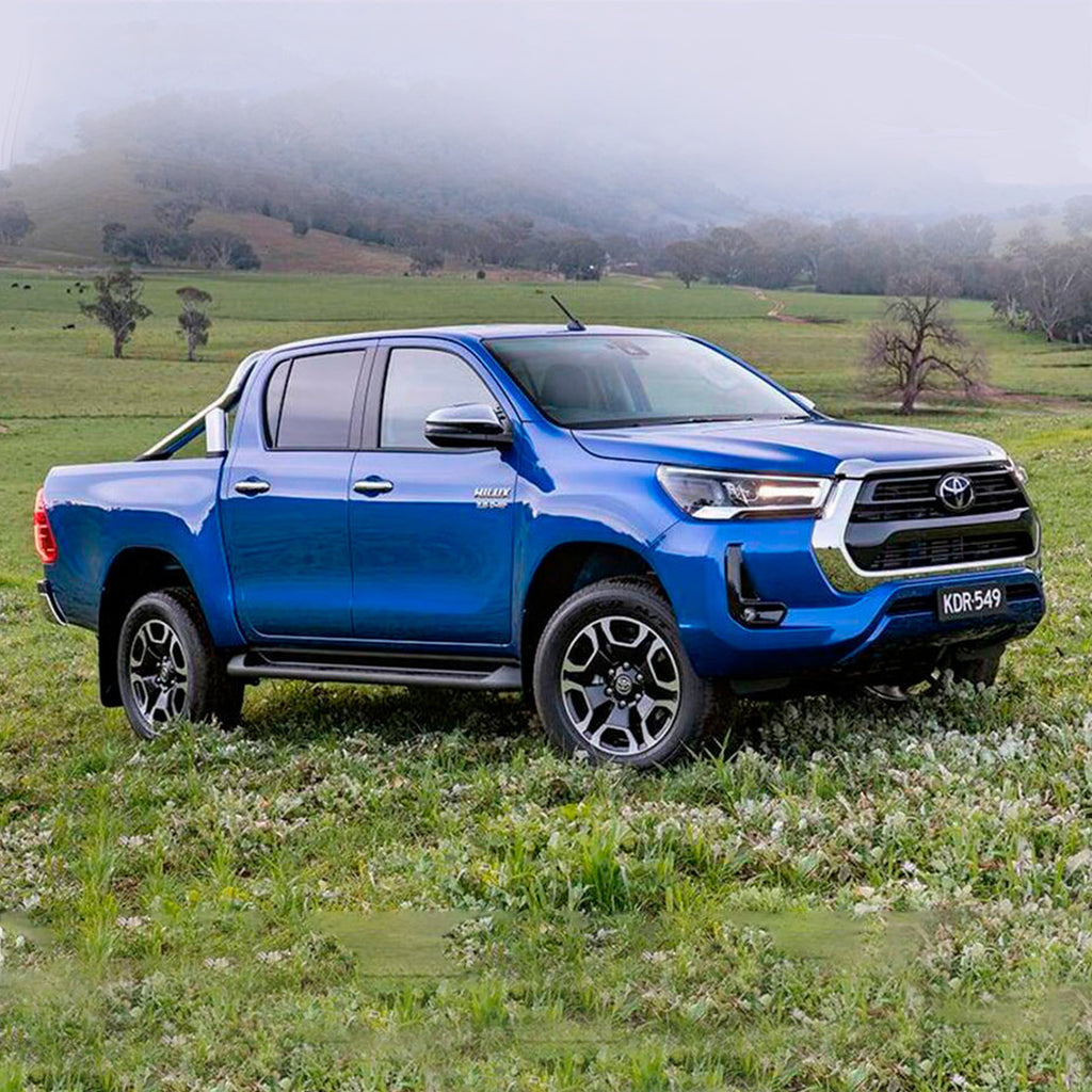 The 2019 Toyota Hilux, equipped with an OME 2.5 - 3 inch Essentials Lift Kit for Hilux Revo, Rocco, SR5 (15-22) - Front Shocks Assembly from Old Man Emu, rests in a field displaying its impressive increased ground clearance.