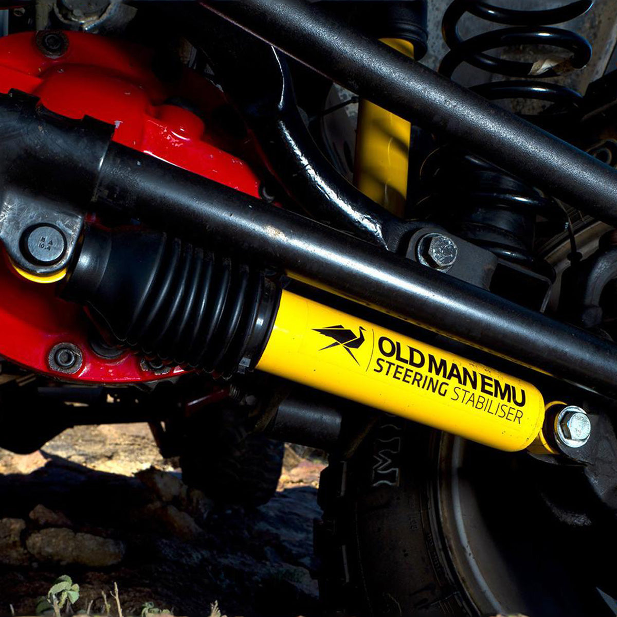 A close up of a yellow and black Old Man Emu suspension system on a motorcycle, emphasizing the ground clearance.