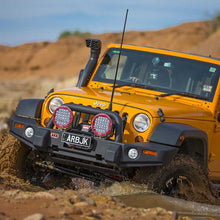 Load image into Gallery viewer, An Old Man Emu-outfitted yellow jeep with the OME 4 inch Lift Kit for Wrangler JK 4 Door (07-18) is confidently navigating through a muddy terrain, effortlessly conquering obstacles with its impressive suspension system and exceptional ground clearance.