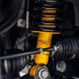 A yellow shock absorber, specifically the Nitrocharger shocks from the Old Man Emu suspension system, is attached to a vehicle to provide increased ground clearance. Now, an OME 2 inch Lift Kit for Jeep Wrangler JL 2 Door (18-23) from the Old Man Emu brand is attached to a vehicle to provide increased ground clearance.