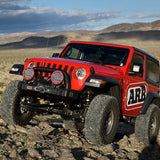 A red Jeep Wrangler JL 2 Door (18-23) with an Old Man Emu OME 2 inch Lift Kit is driving through the desert, equipped with Nitrocharger shocks for increased ground clearance.