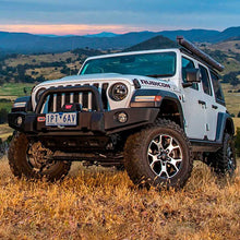 Load image into Gallery viewer, An Old Man Emu Jeep Wrangler JL 4 Door (18-23) with the OME 3.5 inch Lift Kit parked in a picturesque field with majestic mountains in the background.