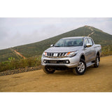 The Mitsubishi Triton, equipped with the Old Man Emu suspension system and Nitrocharger shocks, is parked on a dirt road, showcasing its increased ground clearance.