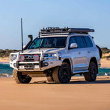 A Toyota Land Cruiser with an OME 1.5 - 2 inch Lift Kit for LandCruiser 200 Series (07-21) by Old Man Emu suspension system and Nitrocharger shocks is parked on the beach, showcasing its exceptional ground clearance.