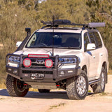 A white Toyota LandCruiser with an Old Man Emu OME 1.5 - 2 inch Lift Kit for LandCruiser 200 Series (07-21) suspension system and Nitrocharger shocks is parked on a dirt road, showcasing its impressive ground clearance.